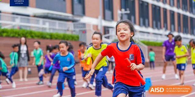 Elementary students from Harrow LiDe School Hengqin smiling and running together during an outdoor sports activity.