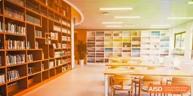 A wide view of the school library showing rows of tables and chairs with shelves of books in the background at the High School Affiliated to Shanghai Jiao Tong University.
