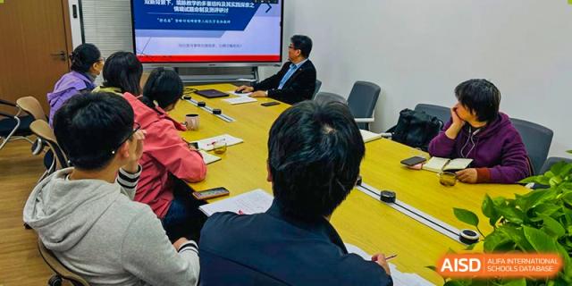 An overhead shot of a person sitting at a large conference table with others during a meeting at the High School Affiliated to Shanghai Jiao Tong University.