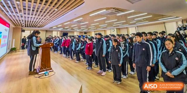 A group of students in uniform standing in a long line in a brightly lit hallway at the High School Affiliated to Shanghai Jiao Tong University.
