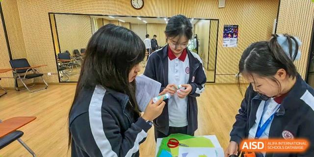 Two students in uniform looking at a mobile phone during a school activity at the High School Affiliated to Shanghai Jiao Tong University.