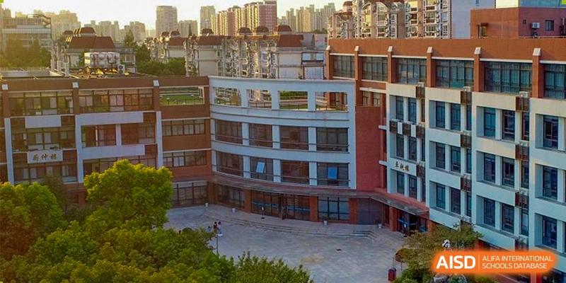 A modern, multi-story school building with large windows at the High School Affiliated to Shanghai Jiao Tong University.