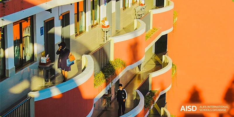A student walking down a sunlit outdoor staircase at the High School Affiliated to Shanghai Jiao Tong University.