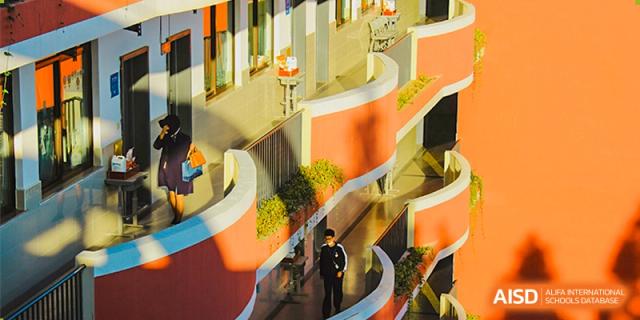 A student walking down a sunlit outdoor staircase at the High School Affiliated to Shanghai Jiao Tong University.