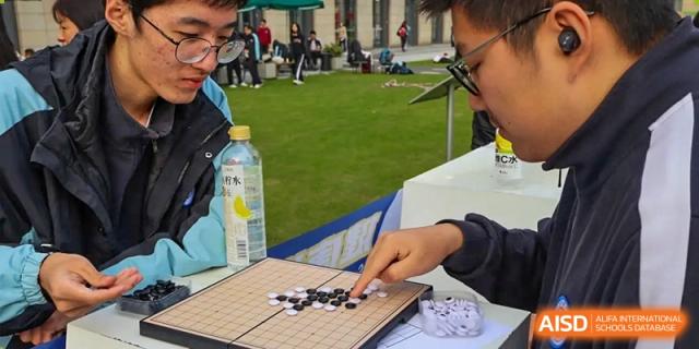Two students playing a game of Go on a board with black and white stones at the High School Affiliated to Shanghai Jiao Tong University.