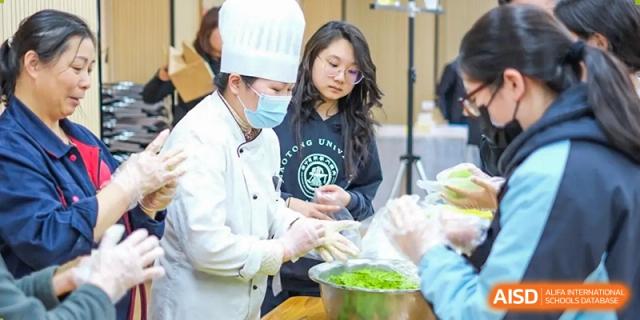 A student wearing glasses and a staff member in a chef's uniform working together to prepare food at the High School Affiliated to Shanghai Jiao Tong University.