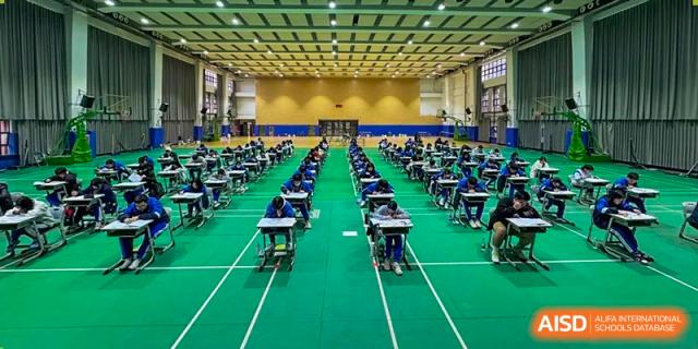 A large hall or classroom set up with individual desks spaced apart for exams or testing at the Guangdong Overseas Chinese High School International Curriculum.