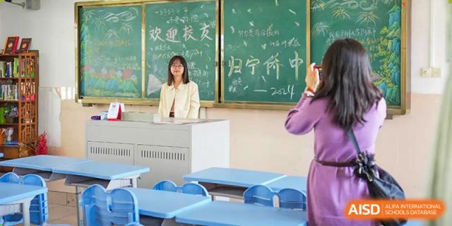 A teacher writing on a chalkboard in a classroom at the Guangdong Overseas Chinese High School International Curriculum.