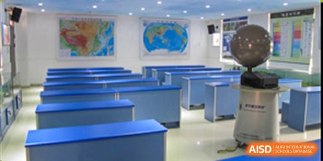 An empty classroom or lecture hall with blue benches at the Guangdong Overseas Chinese High School International Curriculum.