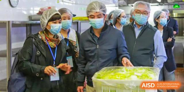 Staff and a student at the Guangdong Overseas Chinese High School International Curriculum serving or receiving healthy food in the cafeteria line.