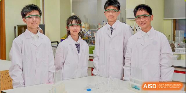 A female student at Wahaha Bilingual School Hangzhou is wearing a lab coat and working in a science lab.