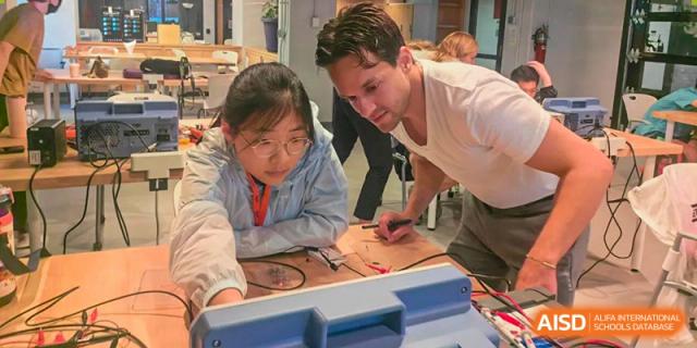 A teacher at Wahaha Bilingual School Hangzhou is helping a student with a hands-on project.