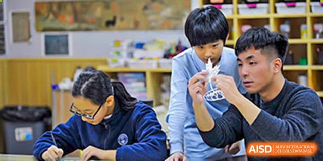 A teacher at Wahaha Bilingual School Hangzhou is assisting a young student with a project.