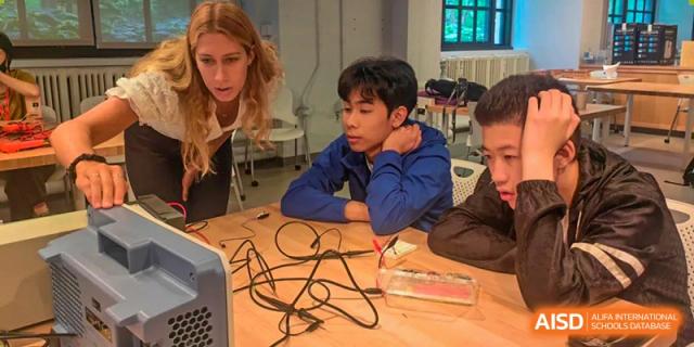 A male student from Wahaha Bilingual School Hangzhou is working on a project with wires and a small motor.