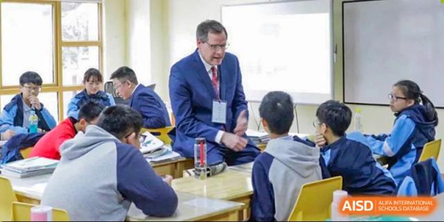 A teacher at Wahaha Bilingual School Hangzhou is standing at the front of a classroom, speaking to students.