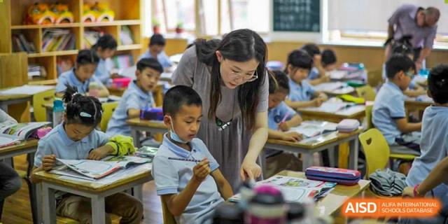 A teacher at Wahaha Bilingual School Hangzhou is helping a young student with their work.