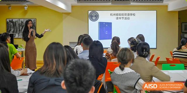 Students at Wahaha Bilingual School Hangzhou are sitting at their desks, listening to a teacher in a classroom.