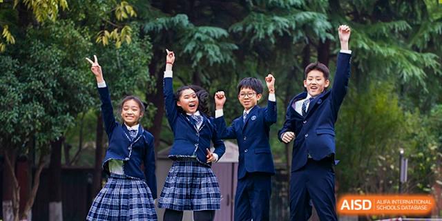 Two students at Wahaha Bilingual School Hangzhou are smiling and celebrating their success outdoors.