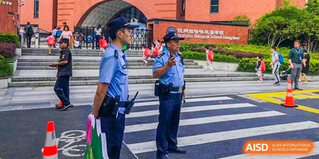 Two police officers are standing at a crosswalk with students in the background at Wahaha Bilingual School Hangzhou.