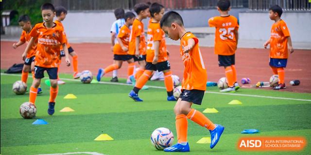 Young male students from Wahaha Bilingual School Hangzhou are playing soccer on a green field.