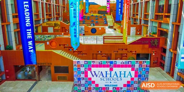 Banners and flags representing Wahaha Bilingual School Hangzhou are hanging in a hallway.