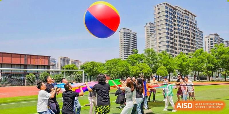 Students from Shanghai United International School Hefei Campus participating in an outdoor group activity with a large balloon.