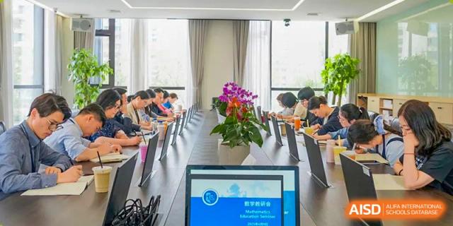 A laptop screen showing a presentation for Shanghai United International School Hefei Campus in a meeting room.