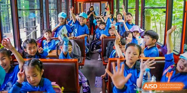 Students from Shanghai United International School Hefei Campus happily waving on a school bus.
