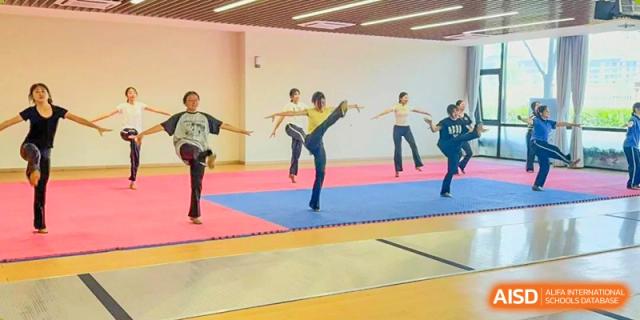 A student from Shanghai United International School Hefei Campus practicing a high kick in a martial arts class.