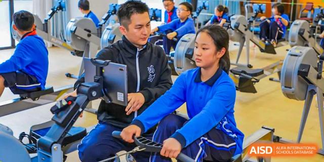 A teacher from Shanghai United International School Hefei Campus instructing students on indoor rowing machines.
