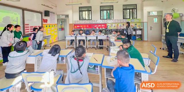 Students from Beanstalk International Bilingual School Kunming working independently or collaboratively at their desks in a busy classroom setting.