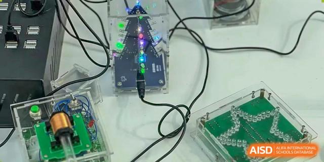 A small, electronic robotics or tech project built by students at Beanstalk International Bilingual School Kunming, featuring blinking lights and wiring on a clear base.