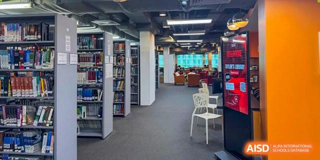 An interior view of the library at Beanstalk International Bilingual School Kunming, featuring tall bookshelves, comfortable seating, and a well-lit study area.