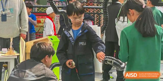 A male student from Beanstalk International Bilingual School Kunming working on a hands-on project or demonstrating a skill outdoors.