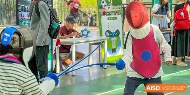 Students at Beanstalk International Bilingual School Kunming engaging in a physical activity or game involving blue weighted ropes on a white table.