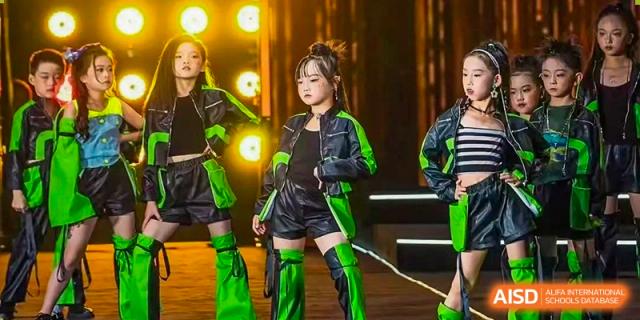 Students from Beanstalk International Bilingual School Kunming in modern, high-energy dance costumes performing on a stage.