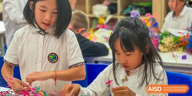 A female student from Beanstalk International Bilingual School Kunming concentrating on a craft project in a classroom, carefully handling small flowers or decorations.