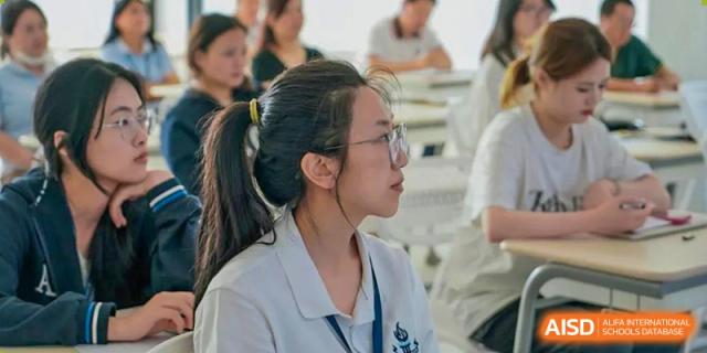 A female student from Adcote School Shanghai is wearing a lab coat and safety goggles in a science class.