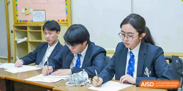 Students from Adcote School Shanghai are seated at desks, using a microscope and taking notes during a science class.