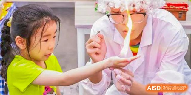 A student from Adcote School Shanghai is in a science lab, holding a test tube during an experiment.