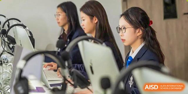 Two female students from Adcote School Shanghai are focused on their work, using a tablet during a class.