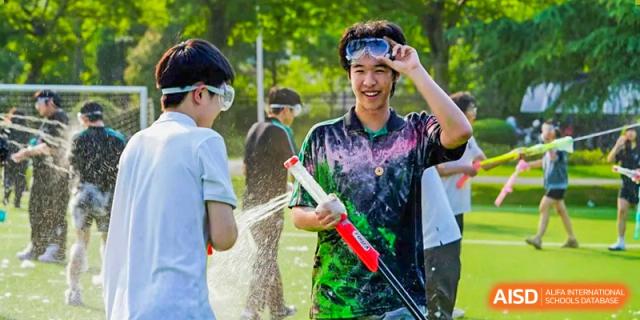 A male student from Adcote School Shanghai smiles while adjusting his goggles, covered in colorful paint, after a water gun fight.