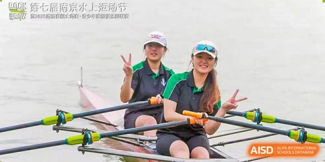 Two female students from Adcote School Shanghai are rowing in a boat during an outdoor water sports activity.