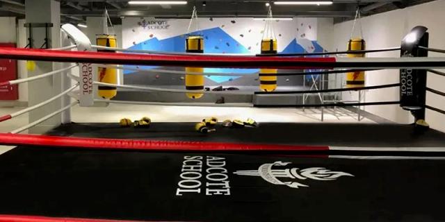 The corner of a wrestling or boxing ring with the "Adcote School Shanghai" logo clearly visible on the side.