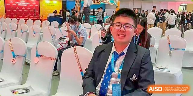 A male student from Adcote School Shanghai smiles for the camera while wearing a suit and a tie with a unique design.
