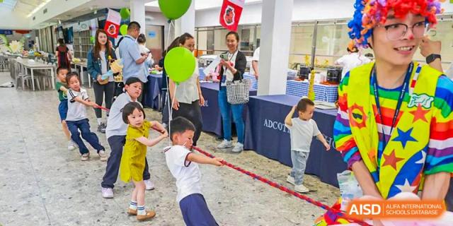 Students from Adcote School Shanghai are playing a game of tug-of-war at a school festival or outdoor event.