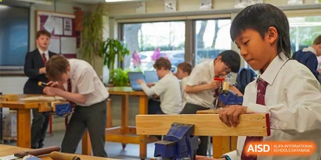 Students working on a project or assignment at wooden tables in a bright, modern classroom at Bromsgrove School Mission Hills.