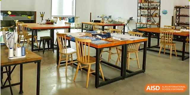An empty classroom with several wooden tables and chairs arranged, waiting for students at Bromsgrove School Mission Hills.