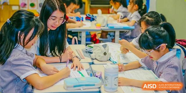 A teacher kneeling to help a group of students with a hands-on project at Bromsgrove School Mission Hills.