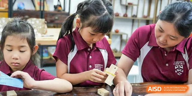 A young female student at Bromsgrove School Mission Hills focusing on a hands-on building project with wooden blocks.